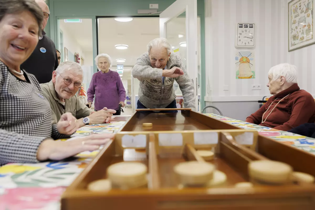 Ouderen zijn samen met vrijwilligers fanatiek aan het sjoelen op KleinGeluk locatie Veldhuis