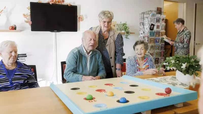 Ouderen spelen samen met een vrijwilliger een spelletje bij KleinGeluk.
