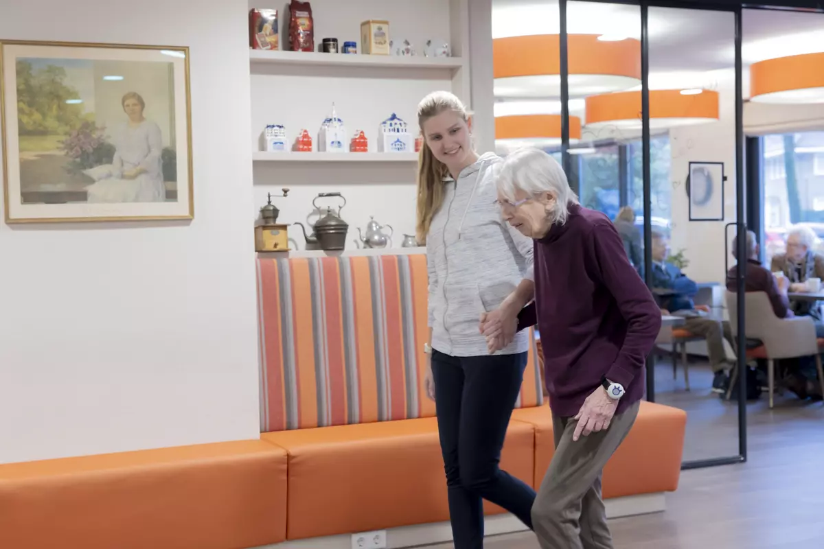 Stagiaire loopt hand in hand met oudere mevrouw