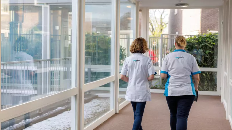 Twee medewerkers van KleinGeluk lopen door de gang van een van de locaties van KleinGeluk