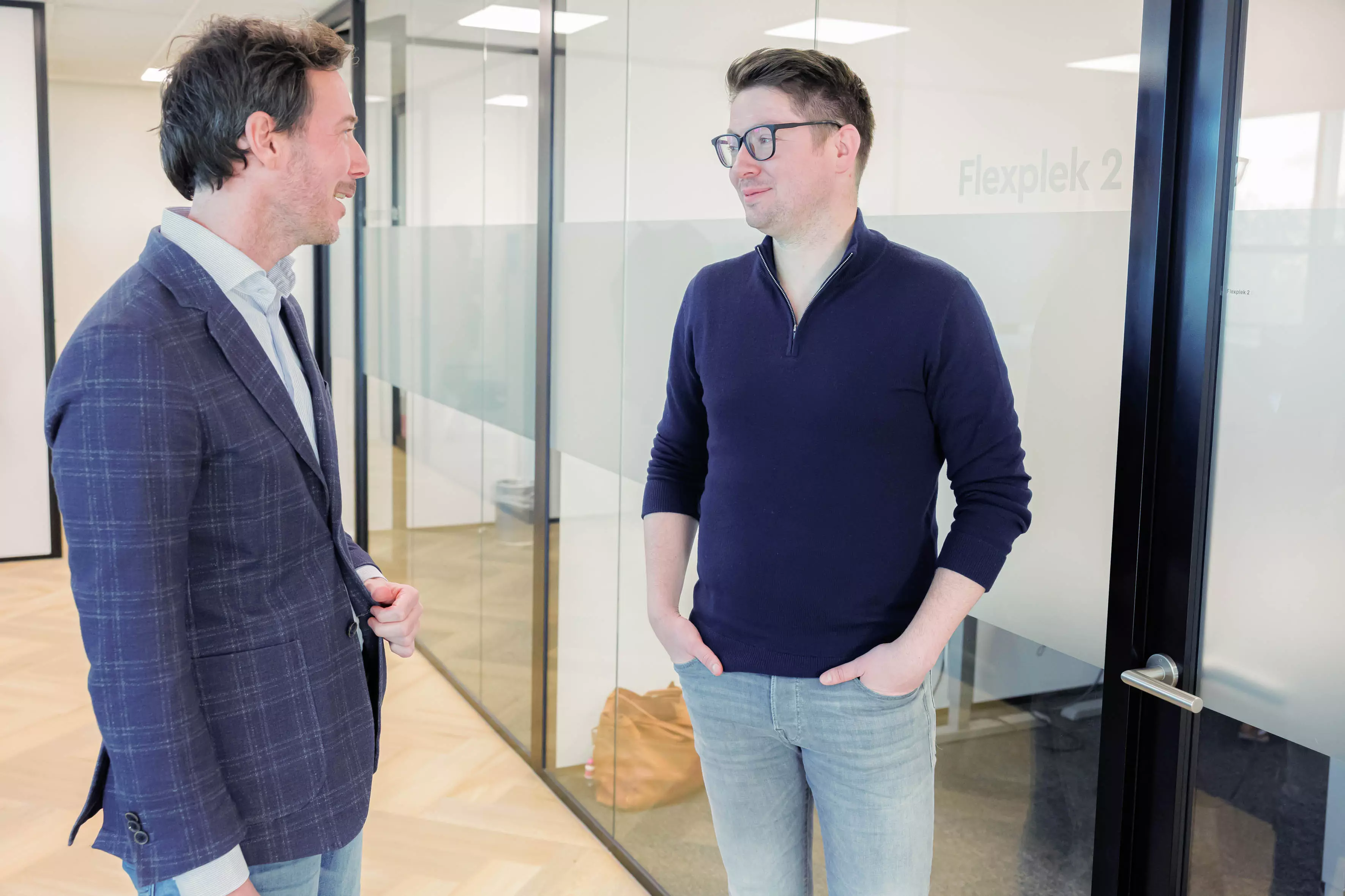 Twee medewerkers van KleinGeluk zijn met elkaar in gesprek op Centraal Kantoor.